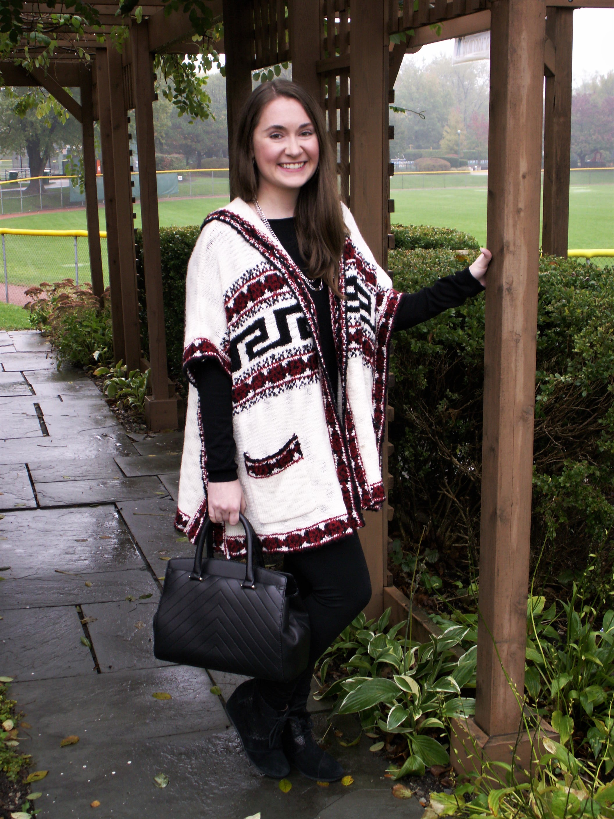 Model is wearing a multi-colored sweater over a black shirt and pair of leggings with trendy accessories.